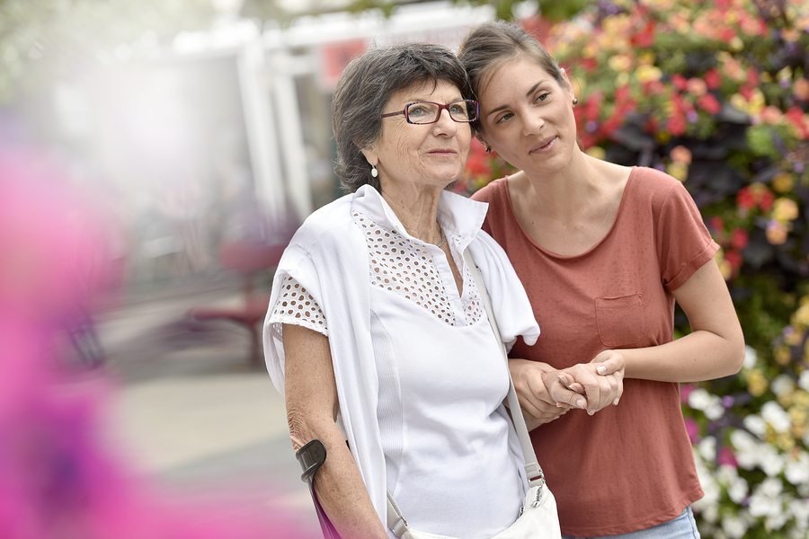 Home carer helping disabled woman walking with crutch