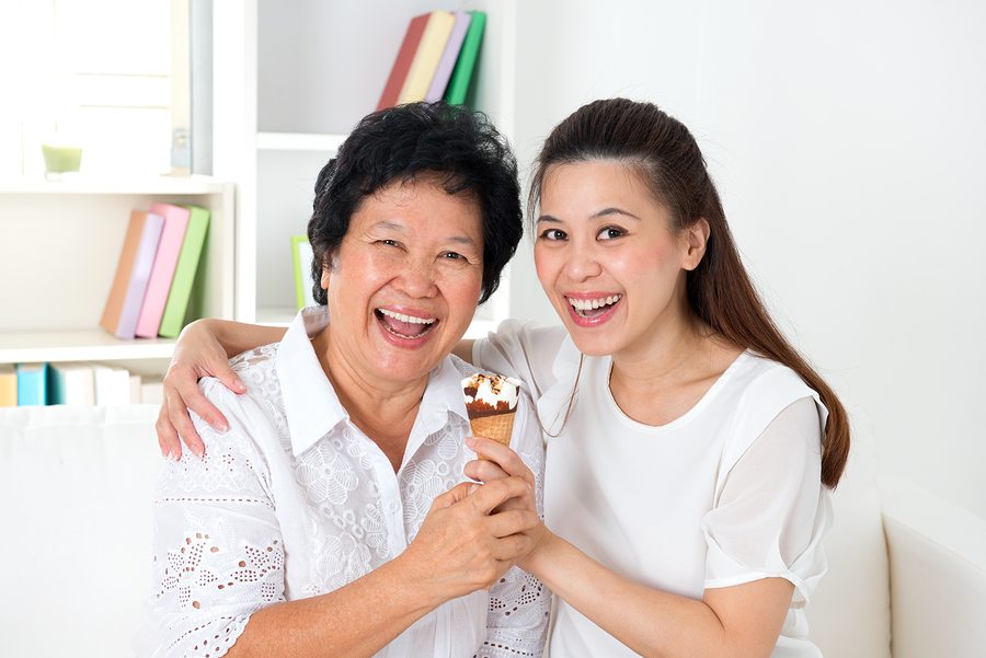 Sharing an ice cream. Happy Asian family sharing food at home. Beautiful senior mother and adult daughter eating dessert together.